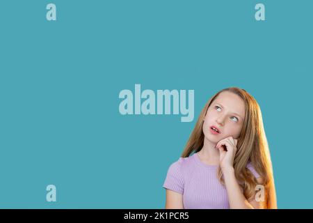 Enfant curieux. Expérience commerciale. Opportunité attrayante. Solution au problème. Portrait d'une jeune fille pensive et perplexe, cherchant à lire en considérant Banque D'Images