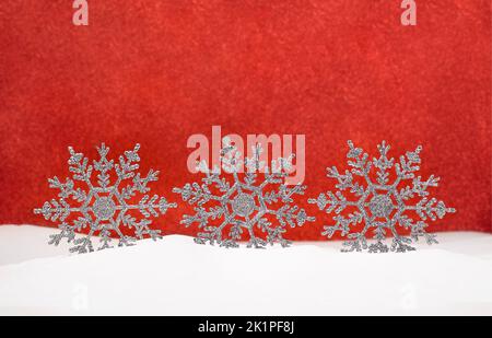 Flocons de neige brillants sur neige avec arrière-plan rouge flou. Noël, nouvel an. Copier l'espace Banque D'Images