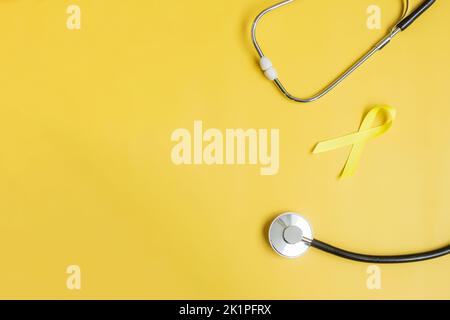 Ruban jaune et stéthoscope sur fond jaune pour soutenir les personnes vivant et malades. Septembre Journée de prévention du suicide, Awaren du cancer de l'enfant Banque D'Images