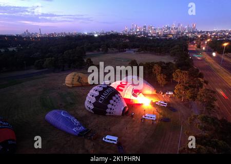 Un groupe de ballons d'air chaud sur le sol se gonfle au coucher du soleil Banque D'Images