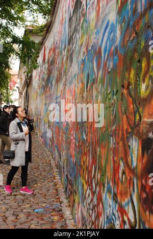 Une femme avec des baskets roses montre le graffiti sur John Lennon Wall à Prague, République Tchèque Banque D'Images