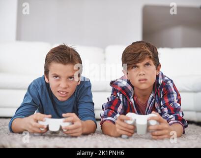 Les jeux deviennent sérieux. Deux jeunes garçons jouant à des jeux vidéo à la maison Banque D'Images