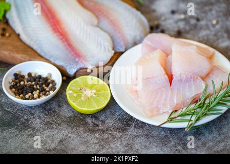 filet de poisson frais brut pangasius aux herbes et aux épices citron vert et romarin, poisson dolly de viande tilapia poisson-chat rayé, filet de poisson sur plaque blanche avec Banque D'Images