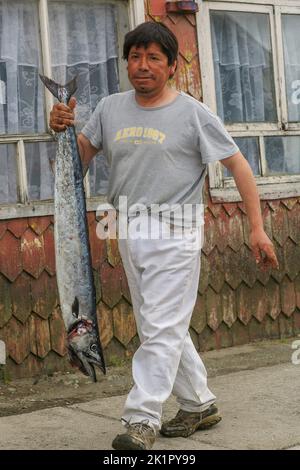 Chili, île Chiloe -man a acheté un poisson et l'apporte à la maison. Il marche le long des maisons traditionnelles construites dans le port de Dalcahue. Banque D'Images