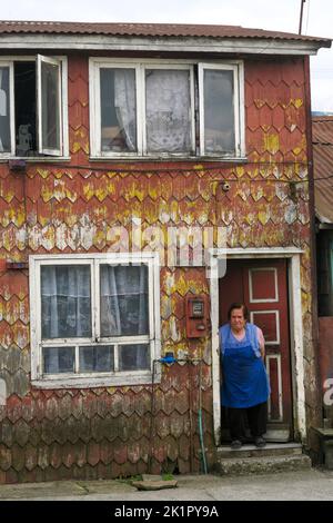 Chili, île de Chiloe - la femme quitte sa maison traditionnelle construite à Dalcahue. Banque D'Images