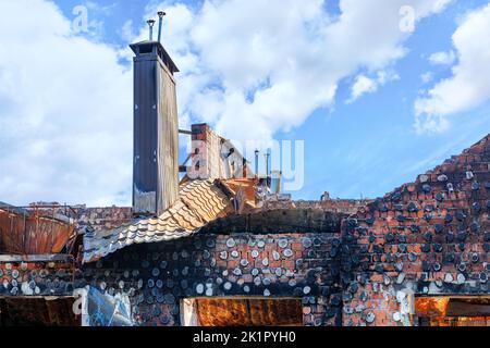 Le toit brûlé d'une maison avec des cheminées de poêle en saillie après le bombardement d'un village ukrainien par des envahisseurs russes. Banque D'Images