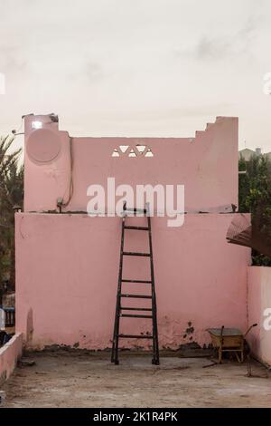 A wooden ladder leaning on an old oink wall inside a rural house in Luxor, Egypt Stock Photo