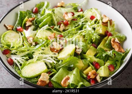 Salade Santé crue avec choux de Bruxelles grenade, avocat, noix et laitue dans le bol sur la table. Horizontale Banque D'Images