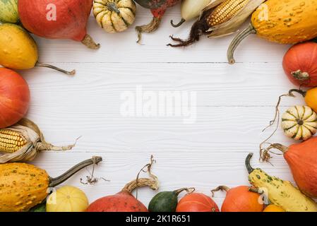 Arrière-plan de vacances de Thanksgiving avec cadre décoratif de récolte de citrouilles, courge d'hiver et cornobs sur table blanche en bois Banque D'Images