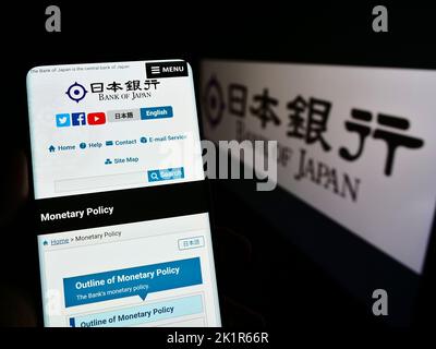 Personne tenant un téléphone portable avec la page web de l'institution financière Bank of Japan (BOJ) à l'écran avec logo. Concentrez-vous sur le centre de l'écran du téléphone. Banque D'Images