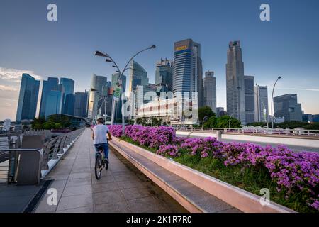 Homme à vélo sur Esplanade Bridge avec vue sur le quartier des affaires en arrière-plan, Marina Bay, Singapour Banque D'Images