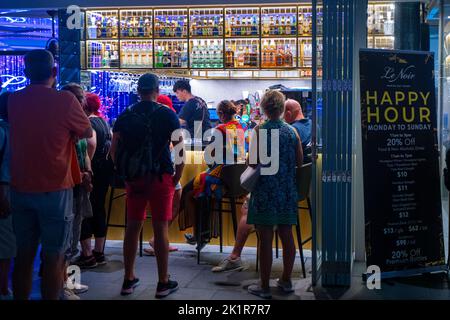 Le panneau Happy Hour et le groupe de clients devant le bar sur le trottoir à Marina Bay, Singapour Banque D'Images