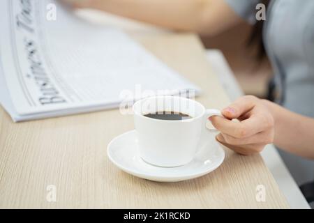 Femme d'affaires au bureau tenant une tasse de café le matin. Banque D'Images