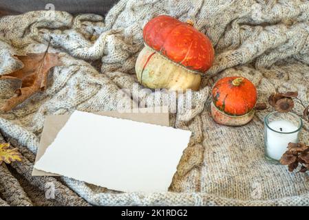 Composition d'automne.maquette de carte de vœux vierge, bougie de feuilles tombées, citrouilles.toile de fond de laine de Plaid.automne, jour d'action de grâces, concept d'halloween.vue du dessus Banque D'Images