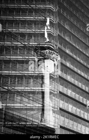 Un cliché vertical en échelle de gris de la tour du Rhin (Rheinturm) à Düsseldorf, en Allemagne, se reflète dans une façade vivivivile Banque D'Images