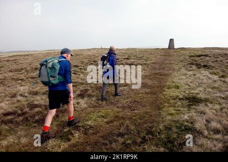 Deux hommes âgés marchant jusqu'au point de Trig Concrete sur le sommet de 'Gragareth' à Kingsdale dans le parc national de Yorkshire Dales, Angleterre, Royaume-Uni. Banque D'Images