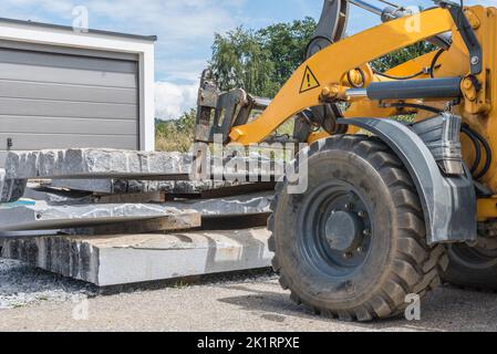 Transporter le granit en pierre naturelle sur le chantier de construction avec une chargeuse sur pneus - chargeur frontal Banque D'Images