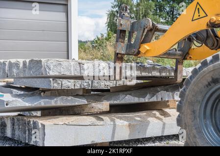 Transport de granit avec chargeur frontal - Pierre naturelle sur chantier et chargeuse sur pneus Banque D'Images