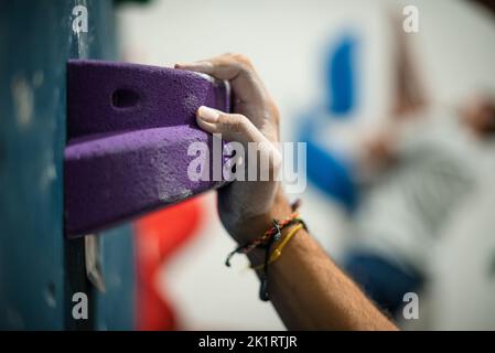 Main tenant sur une prise d'escalade sur un mur d'escalade. Banque D'Images