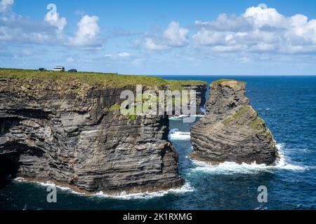 Kilkee, Irlande - 4 août 2022 : les touristes apprécient la visite des falaises de Kilkee avec des véhicules garés à proximité du bord Banque D'Images