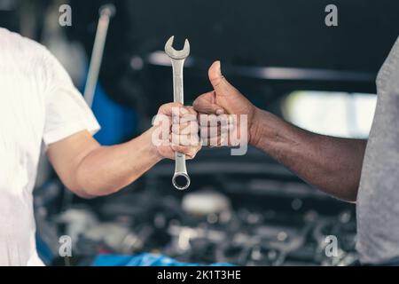 Main du mécanicien de garage avec l'outil. Travail terminé travail fait bon réparer le concept d'entretien de moteur de voiture d'automobile. Banque D'Images