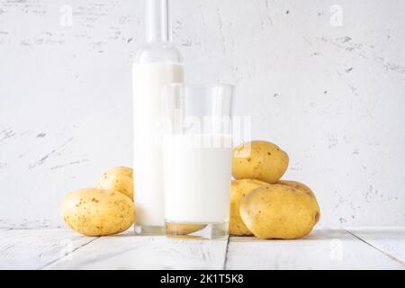 Bouteille en verre de lait de pomme de terre avec pommes de terre Banque D'Images