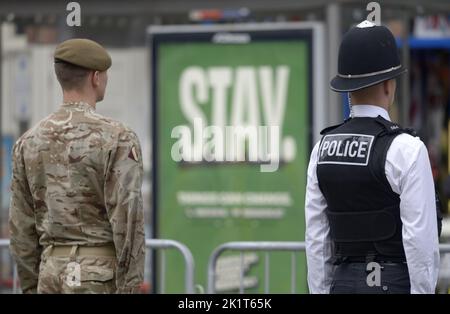 Londres, Royaume-Uni. Le jour du funérailles d'État de la reine Elizabeth II Un soldat et un policier se tenant à l'attention devant la campagne « Stay » Banque D'Images