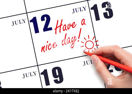 12th jour de juillet. La main écrivant le texte ont une belle journée et dessinant le soleil sur la date calendrier 12 juillet. Enregistrez la date. Mois d'été, jour du Banque D'Images