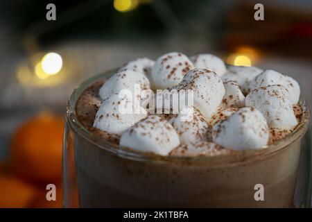 gros plan de mini guimauves sur chocolat chaud dans une tasse en verre, lumières floues arrière-plan Banque D'Images