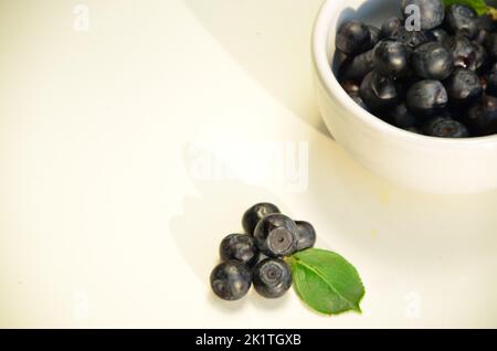 Un bol avec de la myrtille fraîche (Vaccinium myrtillus) sur un vieux banc en bois. Baies sauvages fraîches. Banque D'Images