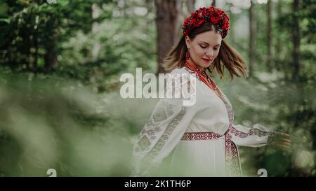 Belle femme ukrainienne dansant dans la forêt de sapins, Carpathian montagnes nature. Fille en robe vyshyvanka à broderie traditionnelle. Ukraine, liberté Banque D'Images