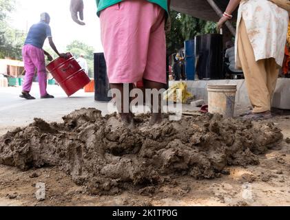 New Delhi, Inde, 11 septembre 2022 - mélange de Mitti avec du bois de paille de blé et du foin de Bhoosa et de l'eau pour préparer un pot cylindrique pour la fabrication du four indien à argile Banque D'Images