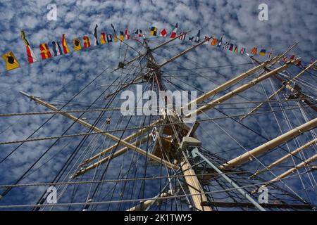 Drapeaux maritimes internationaux sur un mât contre un ciel bleu avec de petits nuages Banque D'Images