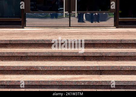 escalier en granit avec marches en pierre s'élève à la porte d'entrée avec poignée en acier inoxydable sur bâtiment façade architecture éclairée par le soleil gros plan, fr Banque D'Images