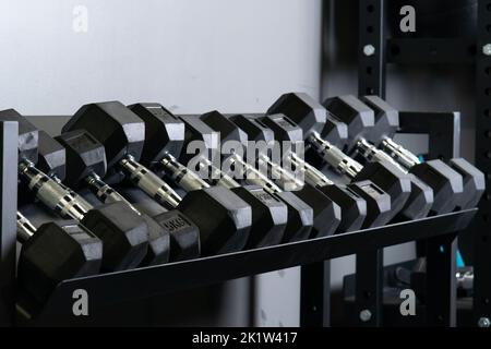 Dumbbbbbbell salle de gym mur flou maison ensemble matériel de stockage, pour les accessoires prenant pour la main noire et musclée, puissance dure. , Banque D'Images