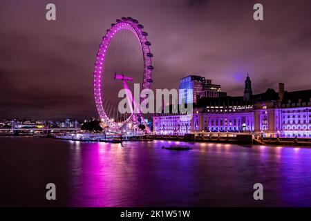 Le London Eye s'illumina en violet la nuit avec la Tamise et le County Hall en arrière-plan Banque D'Images