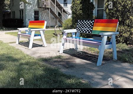 Deux bancs de peinture arc-en-ciel vides sur un trottoir public dans la communauté pro-LGBTQ de Douglas, Michigan. Banque D'Images