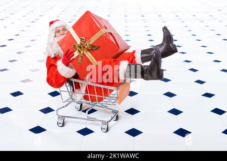 Joyeux Père Noël est assis dans un panier avec une grande boîte de Noël Banque D'Images