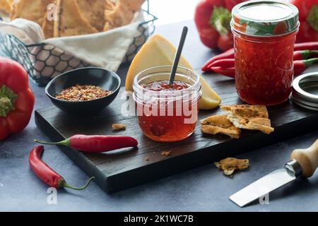 Gros plan des bocaux de gelée épicée de piment chaud servis avec du fromage et des craquelins. Banque D'Images