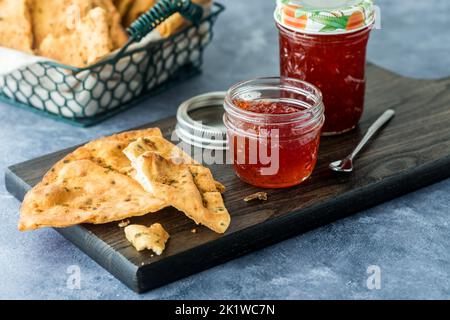 Des bocaux de gelée de piment rouge chaud servis avec des craquelins croustillants à la tortilla. Banque D'Images