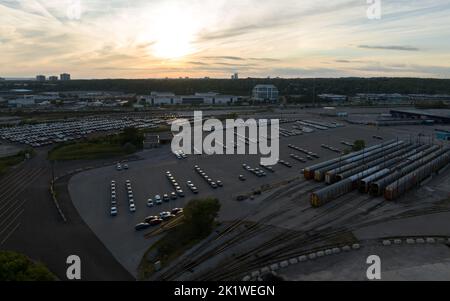 Une vue aérienne au-dessus d'un parking des voitures Ford nouvellement fabriquées en préparation pour le transport par train ou camions, vu comme le soleil se couche. Banque D'Images