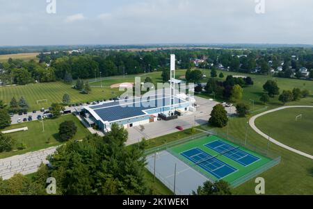 Vue aérienne d'un bâtiment et d'une installation de sport rural avec panneaux solaires installés sur le toit. Banque D'Images