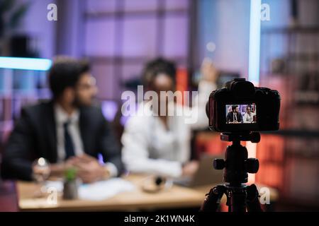 Vue depuis l'écran de l'appareil photo avec des financiers masculins et féminins, un directeur arabe et une femme d'affaires afro-américaine confiante expliquant à leurs collègues des graphiques économiques en ligne sur verre. Banque D'Images