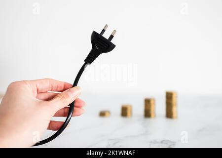 les coûts de l'électricité augmentent image conceptuelle, branchez avec des piles de pièces de plus en plus dans le backgroung, ce qui représente la hausse des prix Banque D'Images