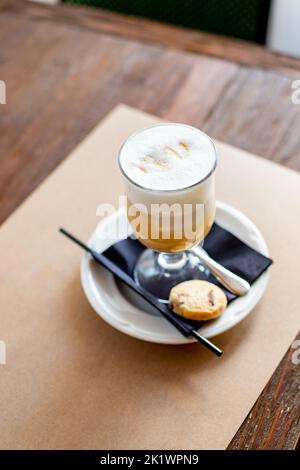 Latte Macchiato en verre de grande taille. Café sur une table au café.café Cappuccino dans un verre élégant avec mousse, paille noire et biscuits.café laiteux Banque D'Images