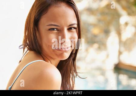 Il est temps de passer l'été. Portrait d'une jeune femme attrayante assise au bord de la piscine. Banque D'Images