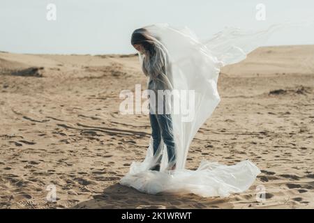 Chagrin féminin. Silhouette défoqué. Isolement solitude. Profil de la femme sans espoir pleure le visage couvrant debout dans le film de polyéthylène volant dans le vent Banque D'Images