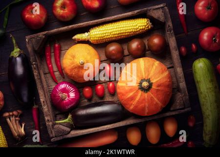 Citrouille, tomate et autres légumes en gros plan dans une boîte de bois récolte d'automne. Fond rustique dans un charriot rustique Banque D'Images