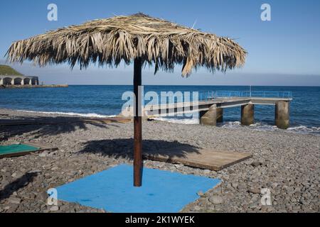 Palmeiras plage à Santa Cruz dans le sud-est de Madère avec un parasol qui a des feuilles pour sa canopée Banque D'Images