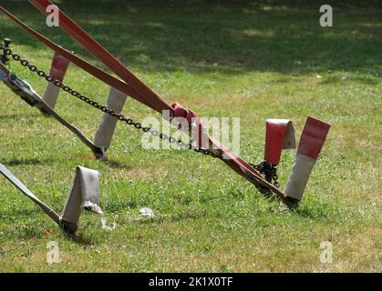 Un gros plan de piquets rouges et blancs pour fixer une tente de cirque avec de l'herbe en arrière-plan Banque D'Images